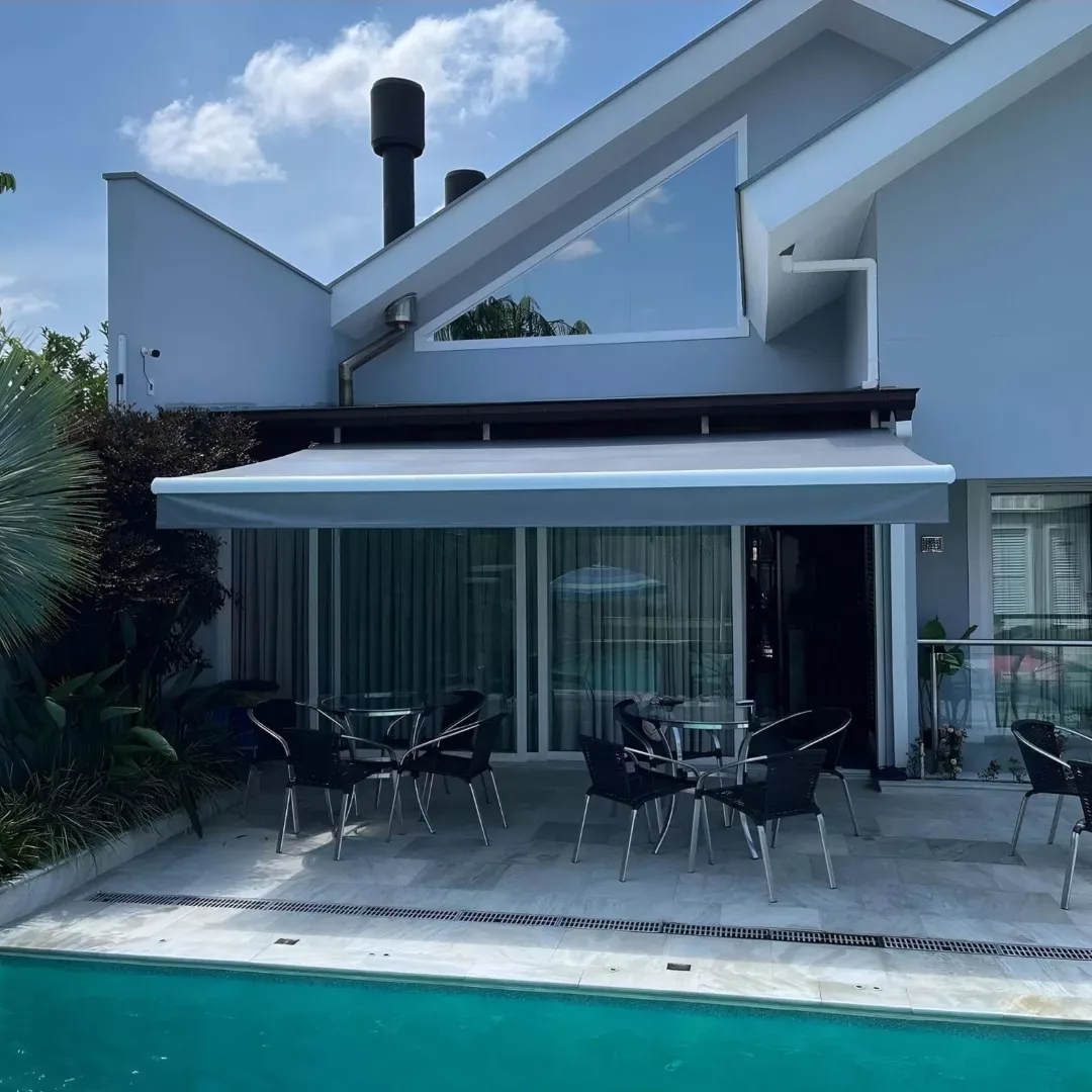Toldo retrátil branco aberto sobre área de piscina residencial